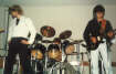 Im Hintergrund Chris an den Drums, rechts Chris an der Gitarre